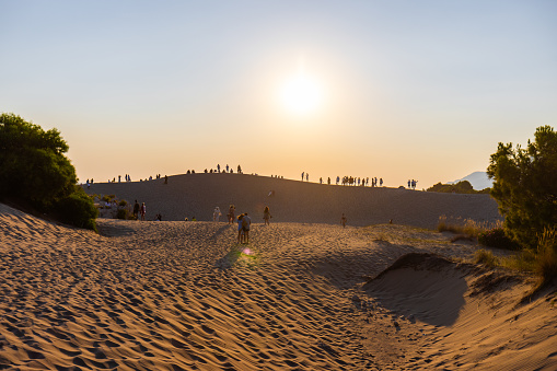 People watching the sunset over the sand dune