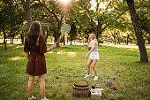 Two female friends playing badminton in the park