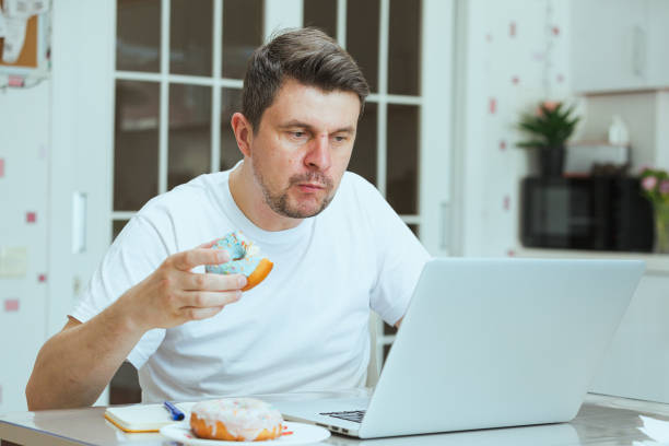 Freelancer man eating unhealthy junk food while working from home. stock photo