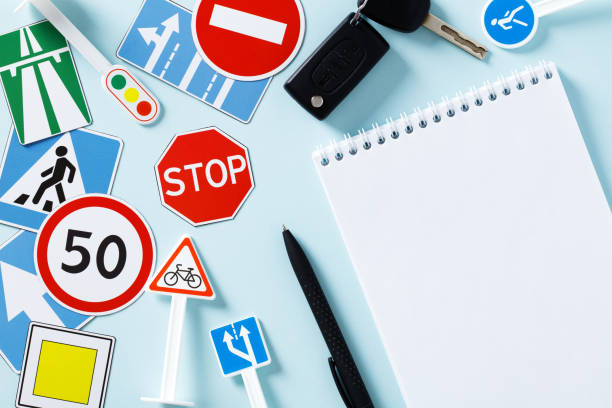 Road traffic signs and blank paper notepad on blue background. Driving school exam concept stock photo