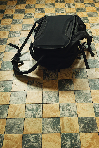 Black backpack on tiled floor in kitchen.