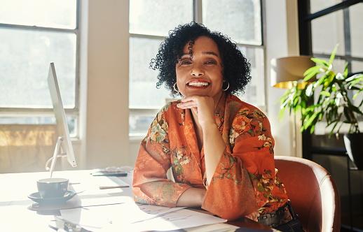 A mature creative business woman sits happily at her desk with her computer. Stock photo, copy space