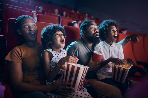 African American family watching a movie in disbelief in cinema. Focus is on girl an mother.