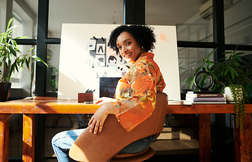 A mature creative designer business woman sitting turned to the side looking at the camera with a visual board in front of her. Stock photo, copy space