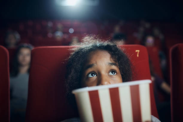 Fearful black girl watching a movie in cinema.