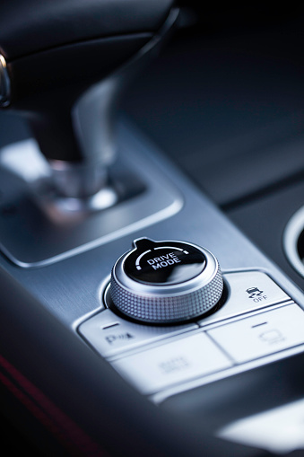 Drive mode dial in a luxury car with gear shifter in background.