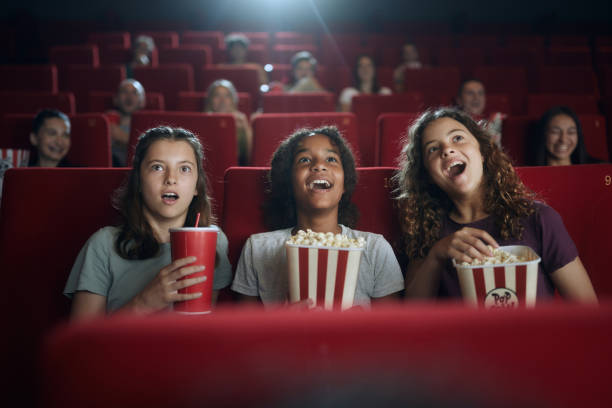 Happy girls watching a surprising movie in theatre. stock photo