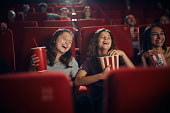 Cheerful little friends watching comedy movie in theatre.