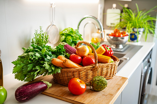 Basket full of fresh vegetables on kitchen counter
