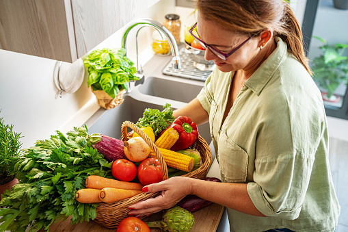 Woman holding basket full of fresh vegetables