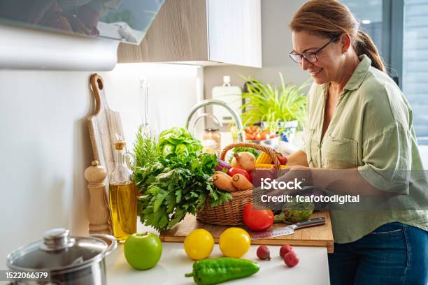 Woman With Basket Full Of Fresh Vegetables In Kitchen Stock Photo - Download Image Now