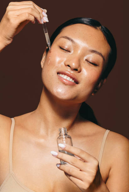 face serum treatment: woman applies beauty serum on her skin - tratamento de pele imagens e fotografias de stock