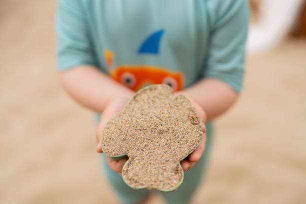 Children's hands in the sand against the backdrop of a sandy beach. Seaside vacation.