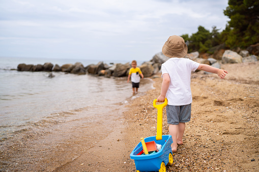 Little girl kid having fun on the beach and playing with sand toys, family summer vacation, Background with empty space for text