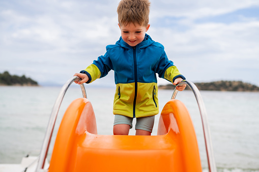 Little boy on pedal boat with a slide.