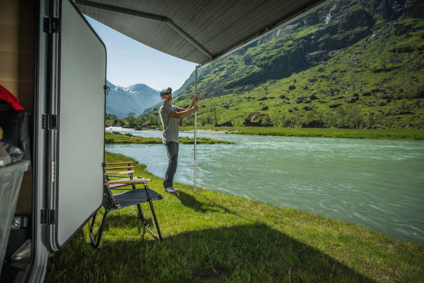 istock Man on a Wild Riverfront Camping Extending His Camper Van RV Retractable Awning 1522182262
