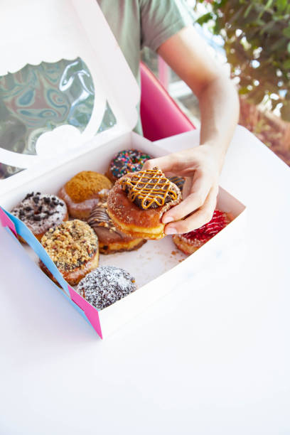 istock Hand lifting a gourmet chocolate brownie doughnut from a box. 1522193606