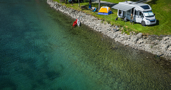 Aerial View of a Water Front RV Park. Camper Van and a Tent Next to Crystal Clear Glacial River