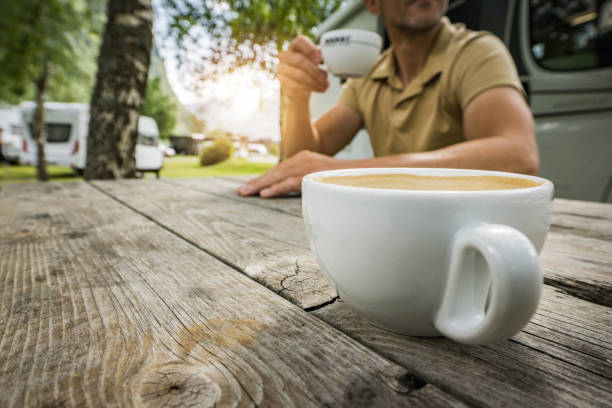 Tourists Drinking Fresh Morning Espresso Made Coffee on a Campground. Getting Ready For the Next Excited Day on the Road.