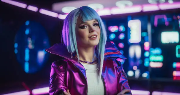 Portrait of a Stylish Cyberpunk Cosplay Model with Blue Hair Posing in Front of Camera, Smiling. Young Happy Beautiful Gamer Girl Looking at Camera in a Futuristic Neon Room