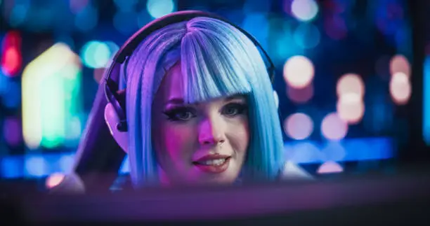 Photo of Close Up Portrait of a Beautiful Young Female Wearing Headphones, Talking with Friends Online on a Computer. Popular Cosplay Streamer Chatting with Internet Fans. Gamer Girl Playing Video Games