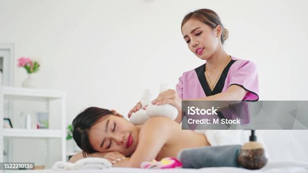 Asian Woman Masseur Using Herbs Hot Ball Therapy Massaging Back Of Woman Client At Spa Salon Therapy Thai Massage Body Care Concept Stock Photo - Download Image Now