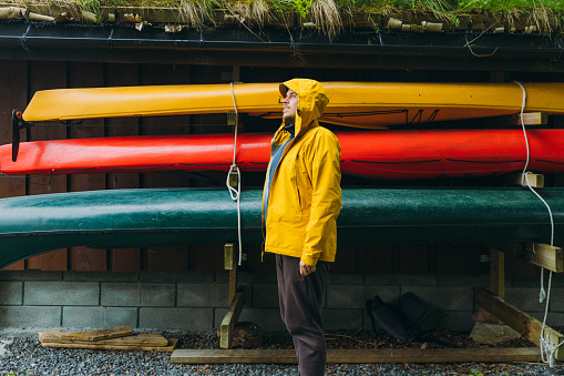 Side View of a male walking by traditional boat house with colorful canoe boats in Scandinavia