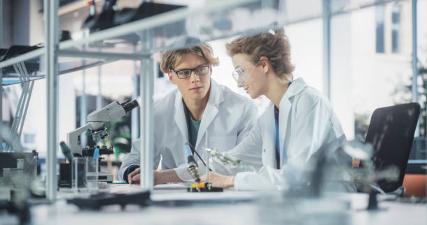 istock Young Female and Male Students Working Together in Laboratory Classroom, Collaborating on a College Research Project. Young Scholars Talking, Study Electronics or Science Engineering 1522244491