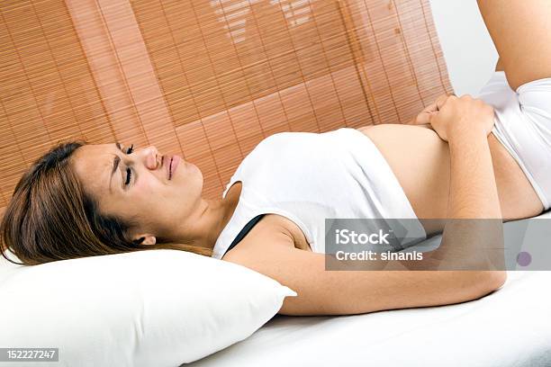 Woman Lying On Bed Suffering From Stomach Pain Stock Photo - Download Image Now - Stomachache, Young Women, Abdomen