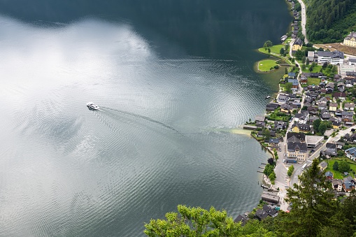Hallstatt, Austria, July 9, 2022: A motorboat is leaving the village of Hallstatt in Upper Austria. Hallstatt is situated in the Salzkammergut region part of which is listed as UNESCO World Heritage Site.