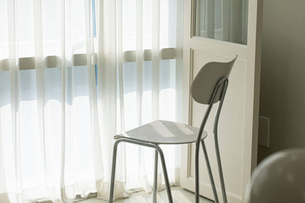 istock white chair on a shiny floor in front of windows with white curtains. 1522283775