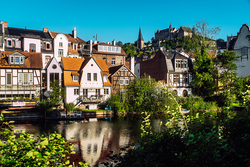 Blue summer morning: Historic Marburg viewed over Lahn river with foreground weir and background castle.