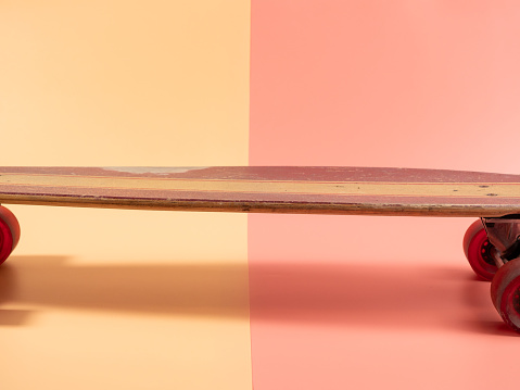 Skateboard on a pink and orange background. Skateboard close up.