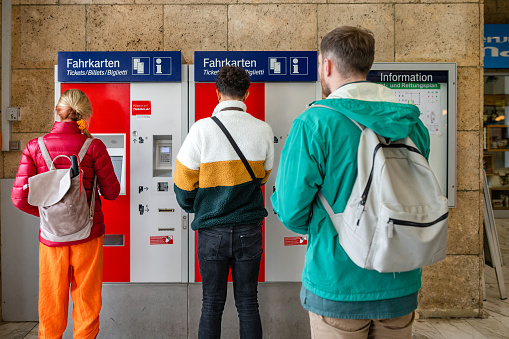 An over the shoulder view of a few friends who are travelling in the European alps. They are collecting tickets in the train station in Garmisch in Germany. They are using contactless to pay for the tickets.