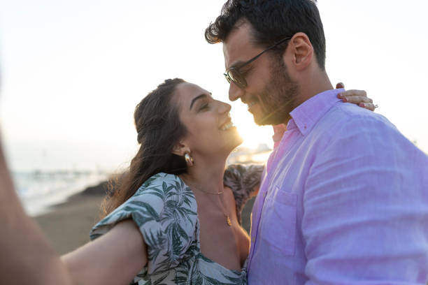 romantyczna zakochana para przytulająca się na świeżym powietrzu podczas zachodu słońca. - beach couple satisfaction playing zdjęcia i obrazy z banku zdjęć