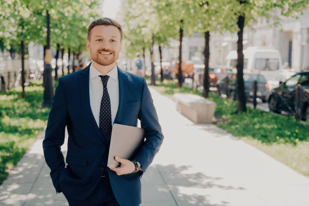 istock Happy office worker in blue suit holds laptop with data, taking break in park, enjoying fresh air. 1522421374