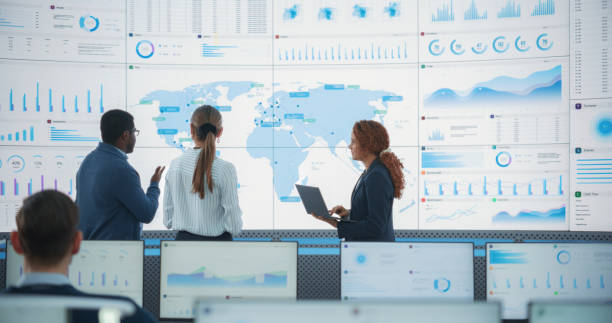 istock Diverse Team Of Specialists From Analytics Department Discussing Global Distribution In Front of Big Digital Screen With World Map In Monitoring Office. Multiethnic Employees Working Behind Computers. 1522422685