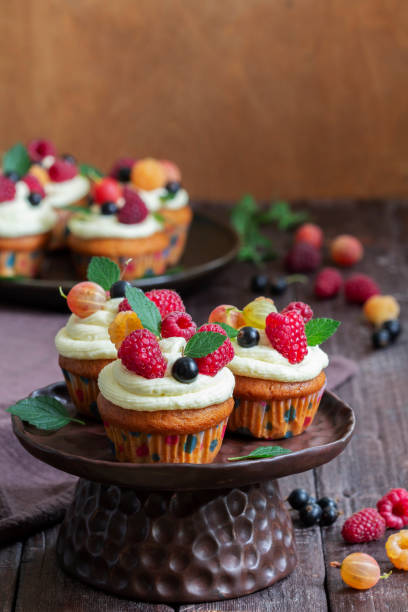 istock Cupcakes with butter cream and raspberry curd, decorated with berries on a wooden surface. 1522425322