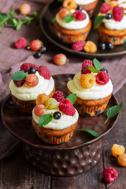 istock Cupcakes with butter cream and raspberry curd, decorated with berries on a wooden surface. 1522425328