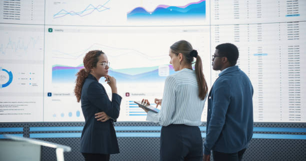 istock Diverse Team Of Data Scientists Analyzing Information And Graphs On Big Led Wall In Modern Monitoring Office. Multiethnic Colleagues Discussing Financial Strategies, Risk Factors, Potential Deals. 1522426055