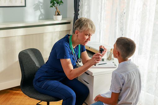 Female doctor examining child's sore throat in her office.