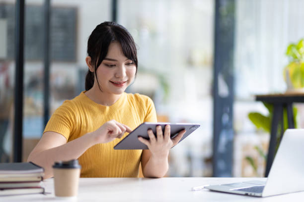 istock Pretty happy Asian woman using tablet to research internet. 1522474971
