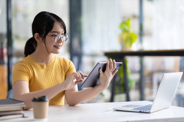 istock Pretty happy Asian woman using tablet to research internet. 1522475482