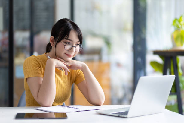istock Happy young asian woman using laptop to browse internet and write study notes. 1522475500