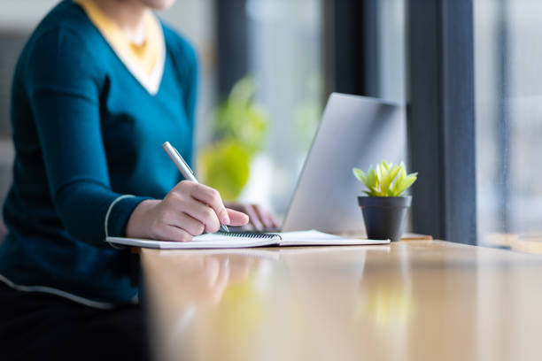 istock Happy young asian woman using laptop to browse internet and write study notes. 1522476583