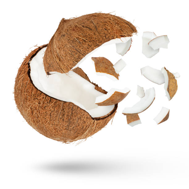 istock Coconut with a flying cap on a white isolated background. Small slices of coconut from it scatter in different directions and cast a shadow from different sides and different sizes. 1522491538