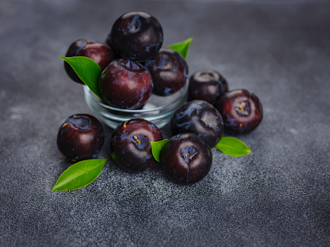 Sweet plums on dark background. Fresh blue plums with leaves. Food fruit Background. Summer postcard. Harvesting in garden, Harvest of plum