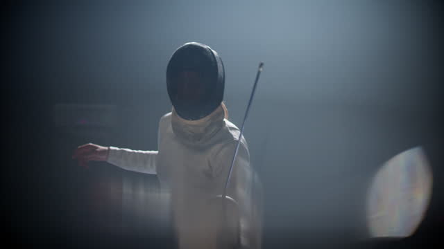 Fencer in combat. Pointing foil sword at camera. Challenging