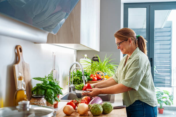 istock Woman washing fresh vegetables in her kitchen sink 1522515565