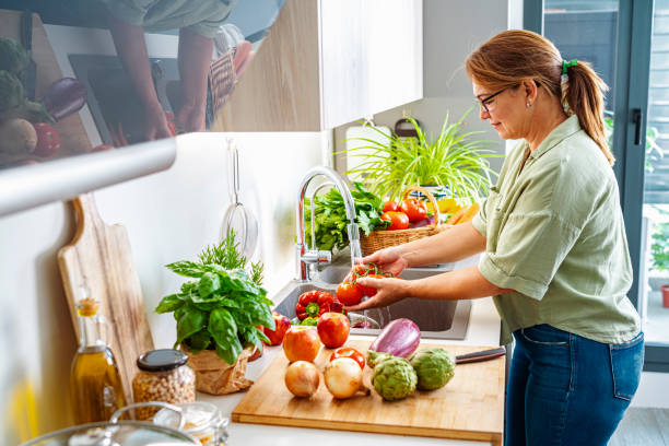 istock Woman washing tomatoes under flowing water 1522516016